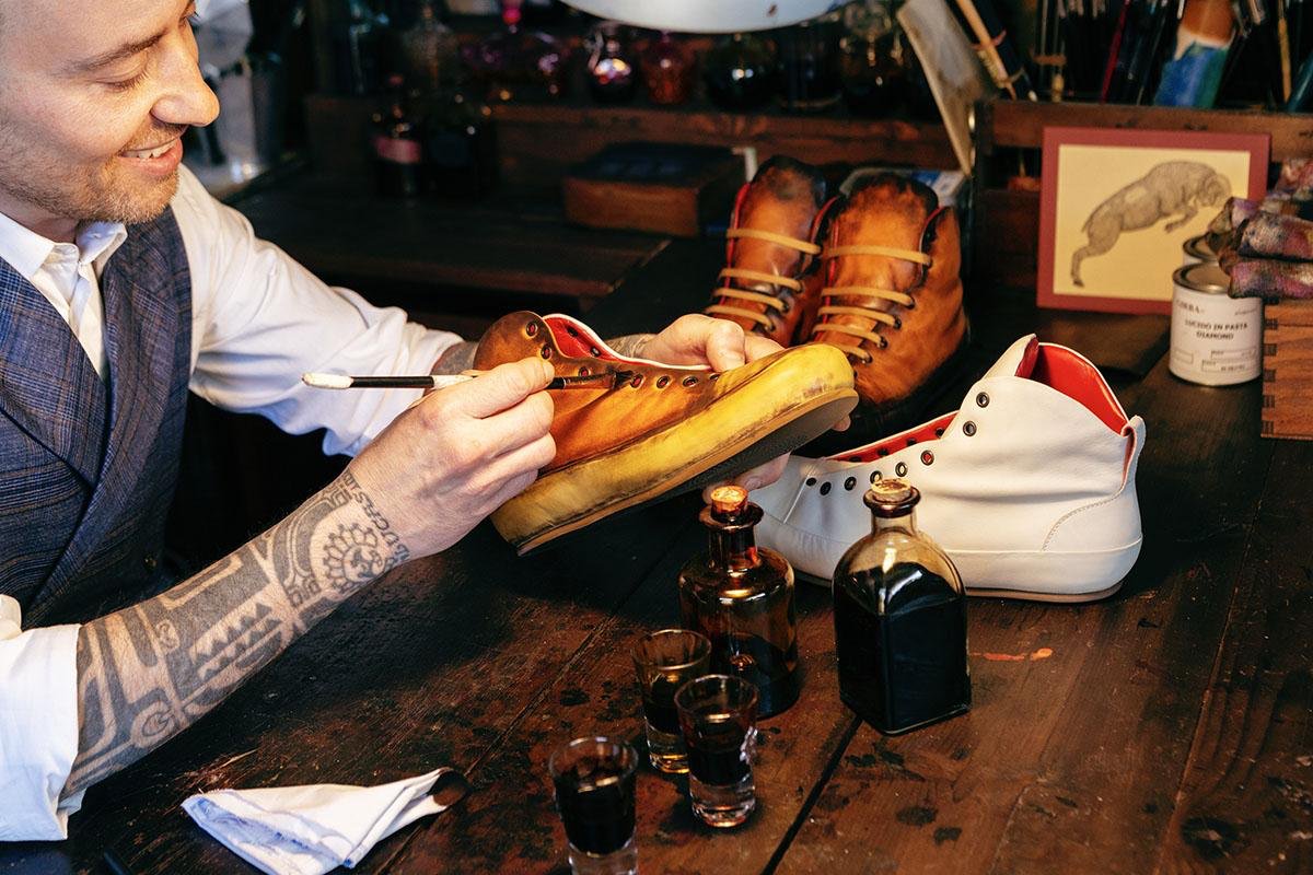An artisan hand-painting a leather sneaker in the Giordano Dieci laboratory