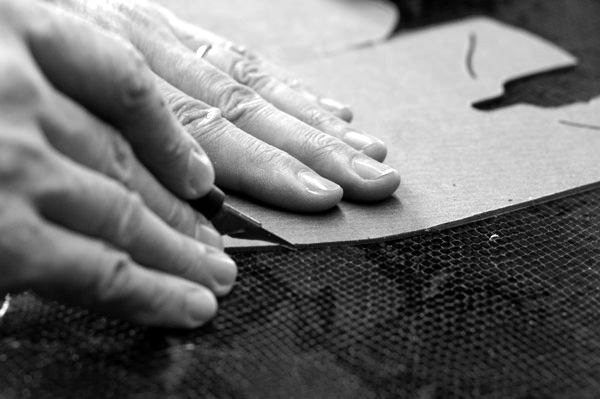Hands laying a paper pattern on leather