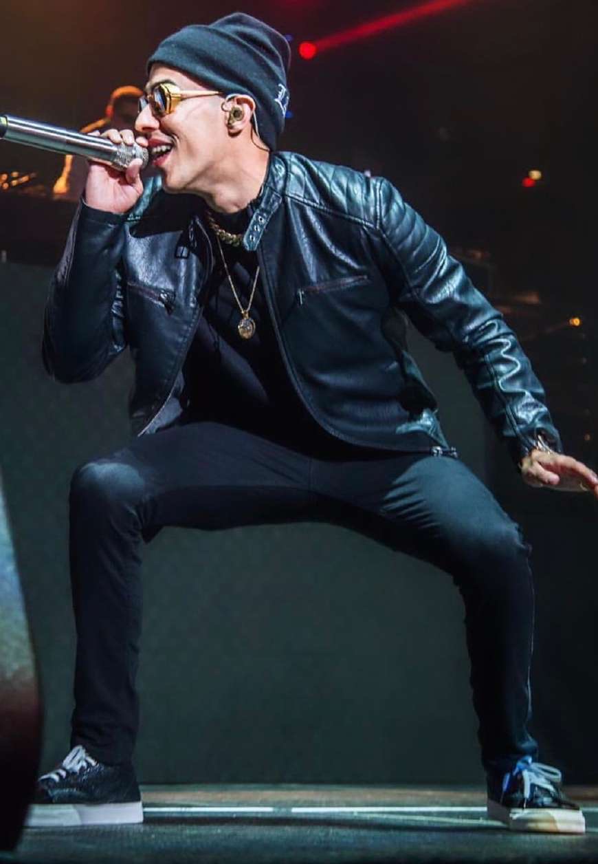 Performer on stage in a black leather jacket and black sneakers