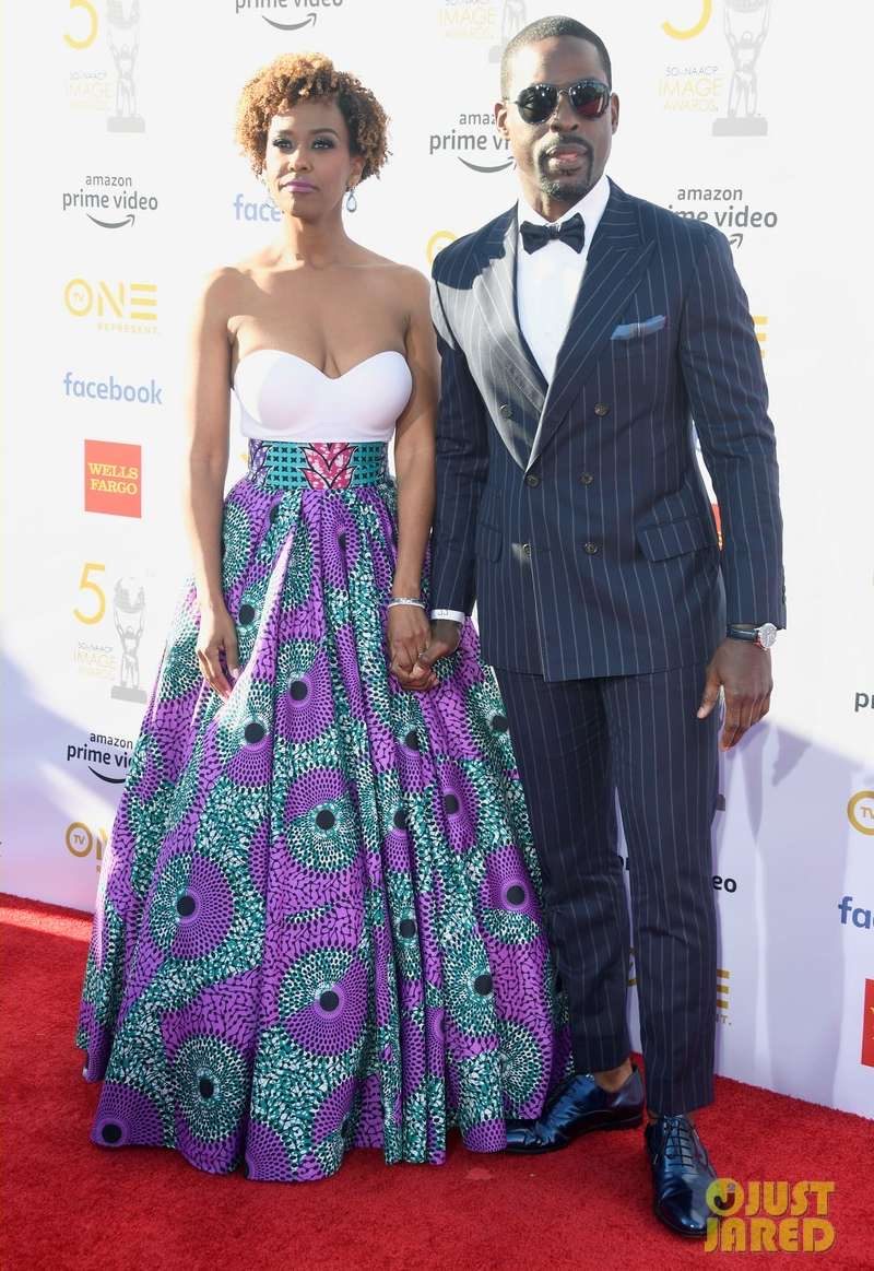 Couple on the red carpet, he in a pinstripe suit and navy patent lace-ups