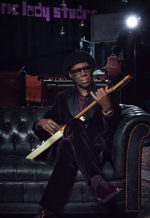 Guitarist on a leather sofa in a velvet suit and burgundy shoes